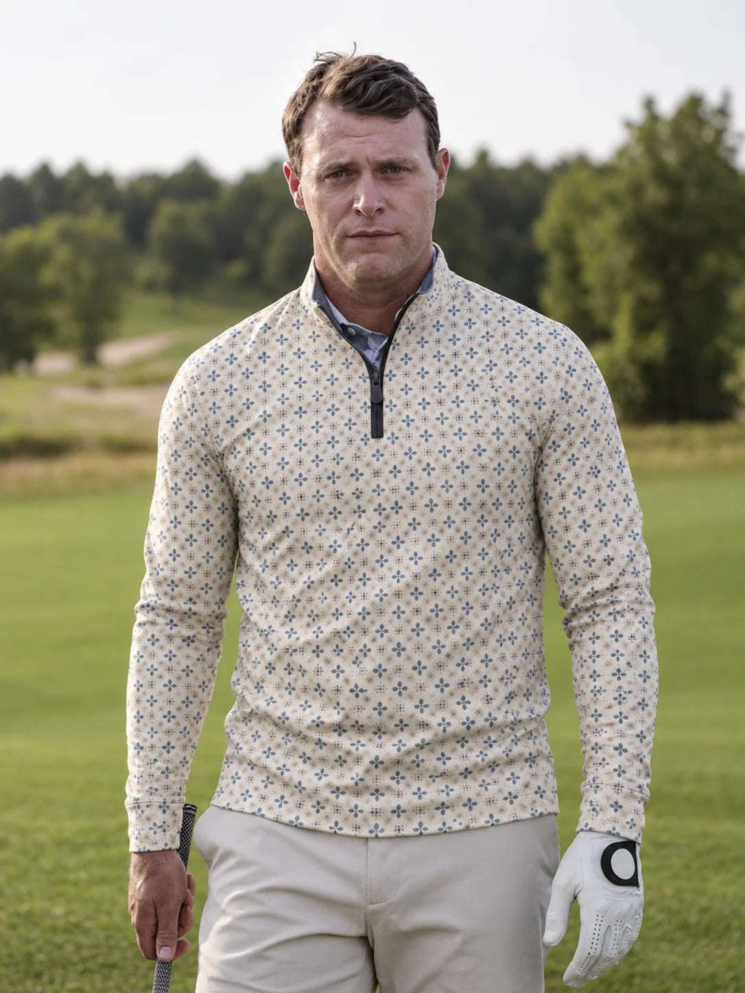 Cremefarbener Golfpullover aus Funktionsmaterial mit blauem Blumenmuster und kurzem Reißverschluss